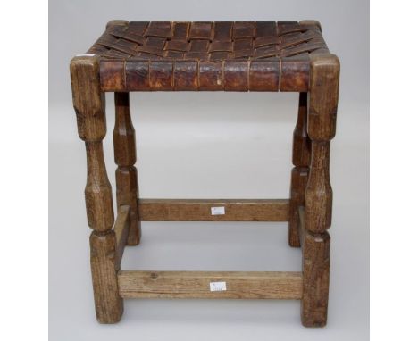 Manner of Robert Thompson (Mouseman), an early 20th century oak stool with woven hide seat on carved turned and block support