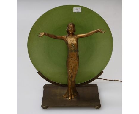 An art deco lamp with a cast gilt metal figure of a female dancer in front of a green glass disc shade, height 33cm overall