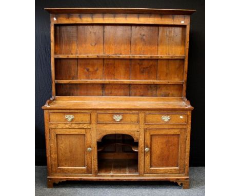 A late 18th century oak tall dresser , the boarded rack with two open shelves, the base having three frieze drawers and two c
