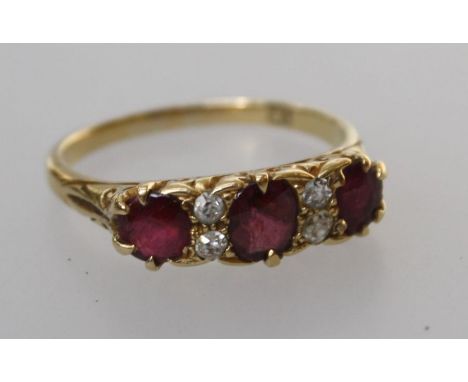 An 18ct ruby and diamond ring, the three oval cut rubies spaced with two pairs of old European cut diamond accents, approx. 3