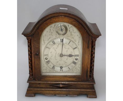 An arched mantel clock, the three train movement having a chiming strike on gongs and a silvered arched dial, raised on brack