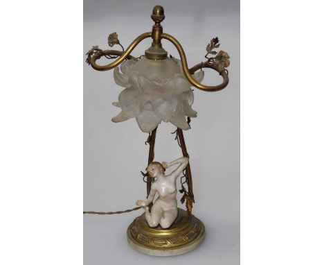 A gilt metal table lamp having a composition female nude under the shade laid on circular base, height 24cm