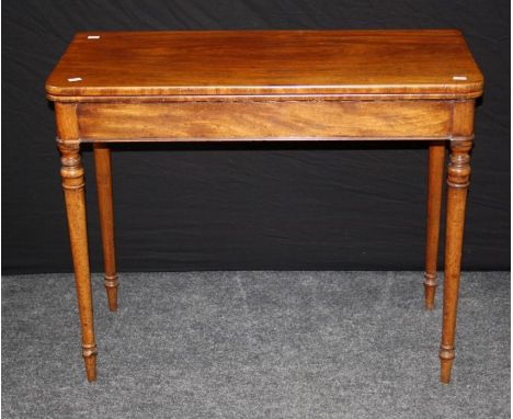 An early 19th century mahogany card table, the beize lined folding rectangular top with double gate support on turned taperin