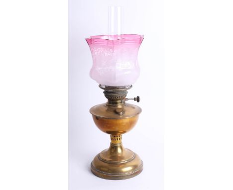 An oil lamp with cranberry shade, height 55cm.