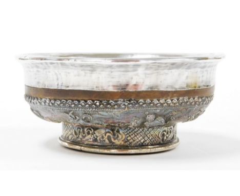 A 19thC Tibetan silver and turned birchwood cup, with a plain insert and fold over rim, the base highly decorated with a band