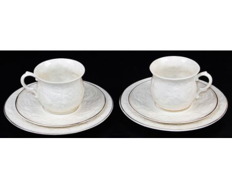 Two Belleek Trios of large cups, saucers and side plates, decorated in the Serenity pattern, the moulded body with tulips, ch