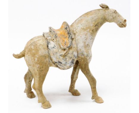 A unglazed Tang Dynasty painted pottery figure of a horse, one foot raised, with detachable saddle, 35cm high. Note: This lot