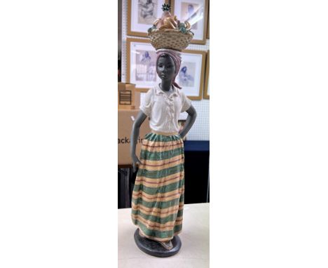 A large Nao figurine of an African Lady balancing a basket of fruit on her head, height 50cm.