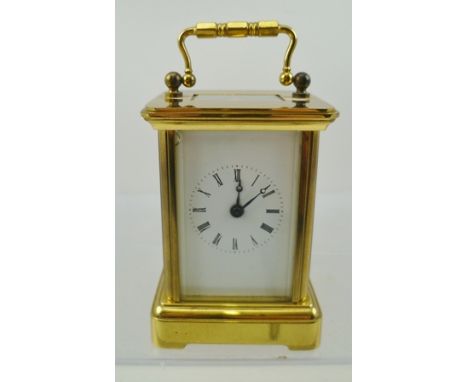 A MINIATURE BRASS CASED CARRIAGE CLOCK, having five bevelled glass panels, white enamel dial with Roman numerals, fitted bale