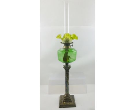 A LATE VICTORIAN OIL LAMP, having green glass reservoir, pale green small petal rim shade and clear chimney, raised upon a si