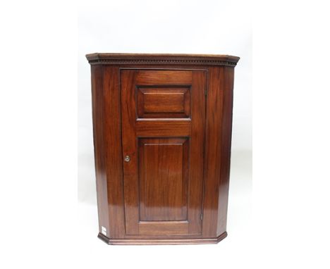A 19TH CENTURY MAHOGANY HANGING CORNER CUPBOARD, having dentil cornice over a single bevelled panel door opening to reveal tw