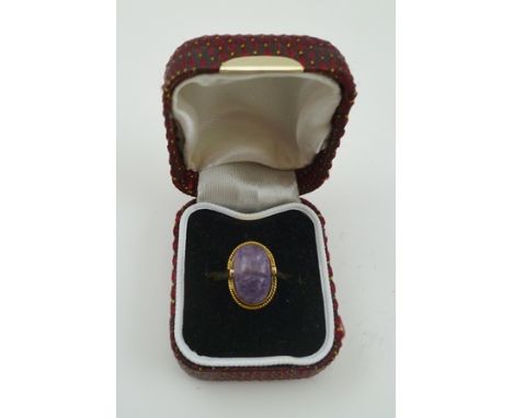 A LADY'S DRESS RING with carved amethyst scarab form stone set in a yellow metal band, considered to be 14k 