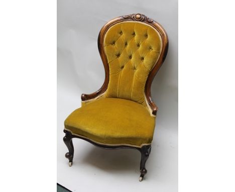 A LATE VICTORIAN NURSING OR SALON CHAIR, having carved polished walnut show wood frame, gold dralon fabric upholstery, button