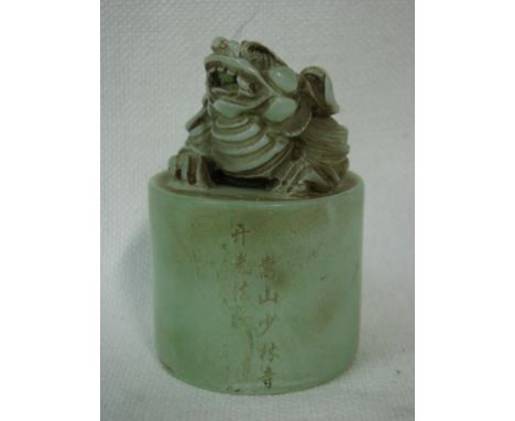 A Chinese celadon jade seal of cylindrical form surmounted by a Dog of Fo, inscribed to side, 8cm high