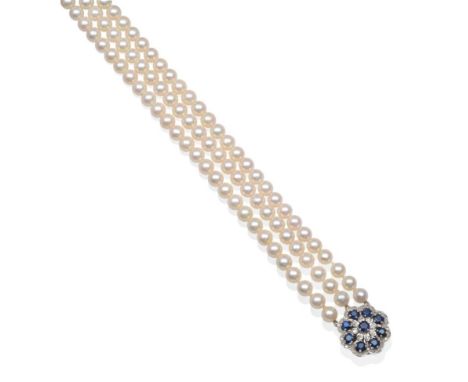 A Triple Strand Cultured Pearl Necklace with a 9 Carat White Gold Sapphire Clasp, uniform cultured pearls knotted to a clasp 