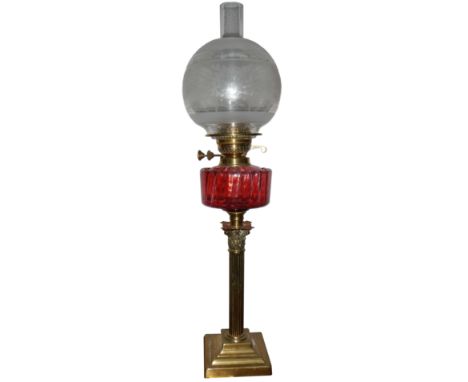 A brass Corinthian column oil lamp with cranberry glass font and original shade