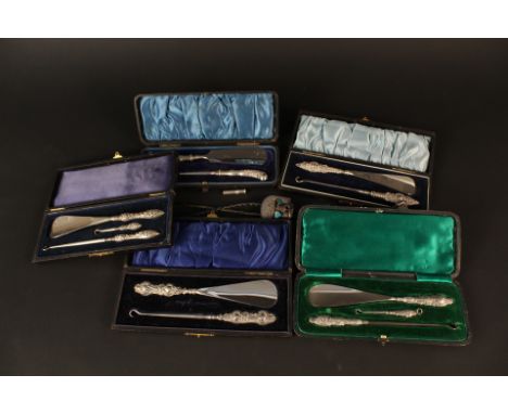 Five cased sets of silver handled shoe horn and button hooks together with a braided leather necklace with white metal mounts