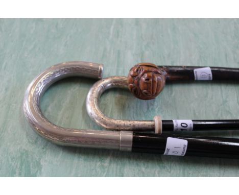 A walking stick with silver grip, one other with white metal grip and a carved wooden dogs head stick