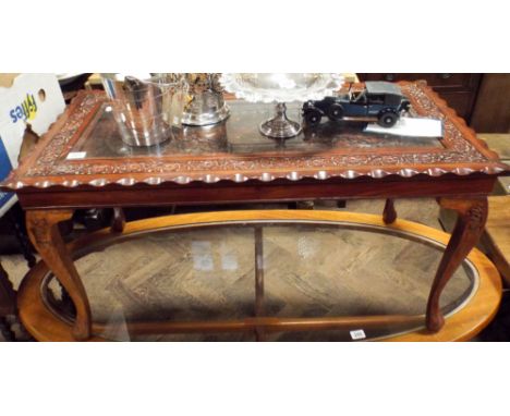 Indonesian carved hardwood coffee table with an inset decorative panel and glass top 