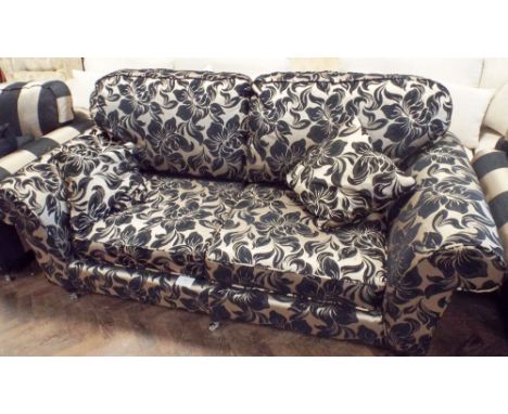 A contemporary three piece lounge suite in black and gold, comprising of large two seated sofa in a floral covering with loos