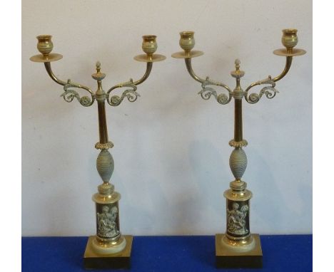 A pair of two-light French Empire style brass candelabra, the two candle-arms above a stem with stylised stiff leaves above a