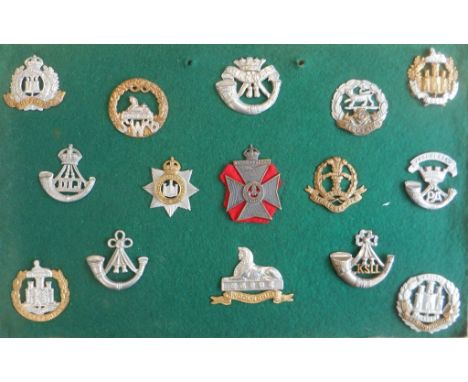 Fifteen, mostly light infantry, cap badges mounted on a display board: the Suffolk Regiment (bimetal); the South Wales Border