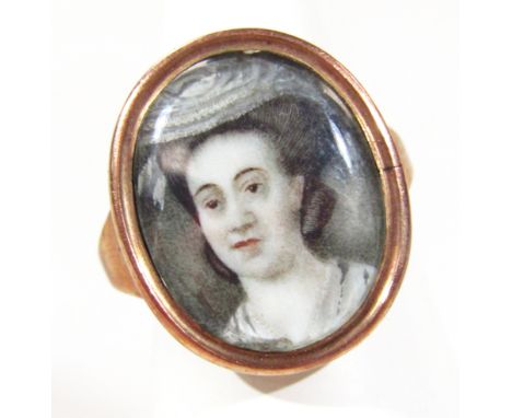 A 19thC portrait ring, the oval centre handpainted with a lady quarter profile wearing an elaborate hat with hair up, waterco
