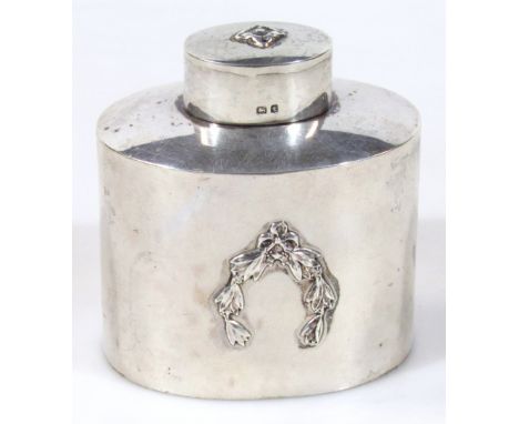 A George V silver tea caddy, by Albert Edward Jones, the cylindrical body with oval lid, raised with flower head and garlands