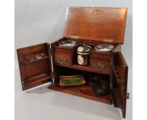 A late Edwardian smoker's cabinet, of rectangular outline, the hinged lid with moulded outline revealing a fitted interior wi