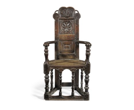 A rare James I joined oak caqueteuse open armchair, Scottish, dated 1606Having a tall narrow back, with arched pierced and ca