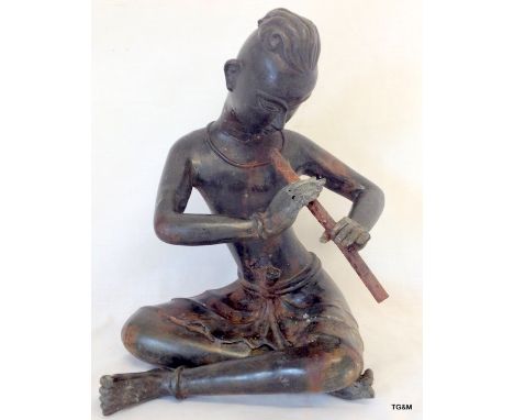 An antique Bahli metal figure of a man playing a flute