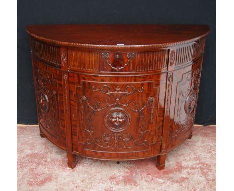 Mahogany commode of demi-lune shape in the 18th century style, with a drawer above a cupboard door enclosing a shelf, decorat