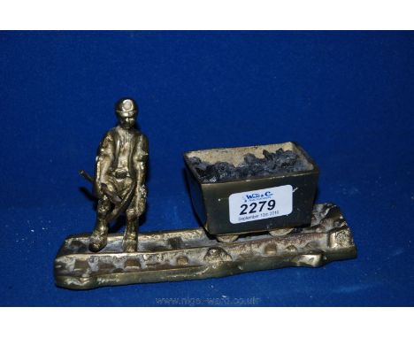 A small Brass ornament depicting a Miner with pick axe and cart on rail track