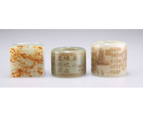 THREE JADE THUMB RINGS one carved in the round with script between Greek key borders; another carved in the round with script