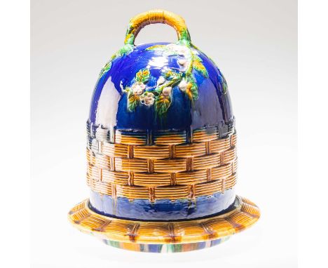 A MINTON STYLE MAJOLICA CHEESE DOME modelled as a skep with trailing blossoms and a branch handle, on a similarly decorated p