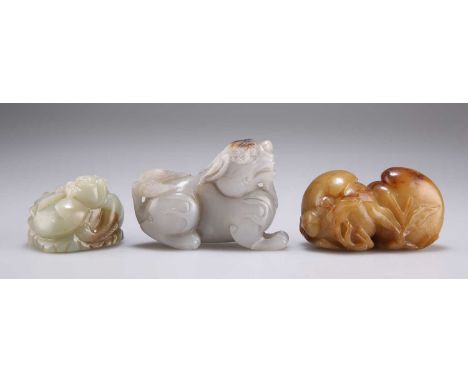 THREE JADE CARVINGS comprising A RECUMBENT QILIN, (a/f), 6cm by 8.5cm; A PLAYING QILIN GROUP, 4.5cm by 5.5cm; and A PEACH AND