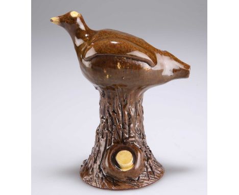 AN EARLY 19TH CENTURY SLIPWARE BIRD WHISTLE possibly Halifax, modelled perching upon a tapering trunk, in brown and cream gla