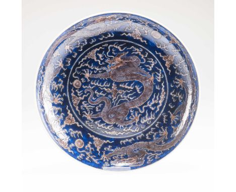 A CHINESE UNDERGLAZE BLUE AND COPPER-RED 'DRAGON' CHARGER of large proportions, painted to the central well with a five-clawe