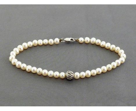A freshwater cultured pearl bracelet, composed of uniform 4.8mm pearls, with white metal (tests 18 carat gold) spacer and lob
