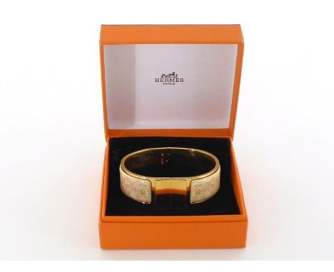 HERMES, a silver gilt and printed enamel bracelet, with beige on white foliate pattern, 6.2cm inner diameter, 67.1gms, in its