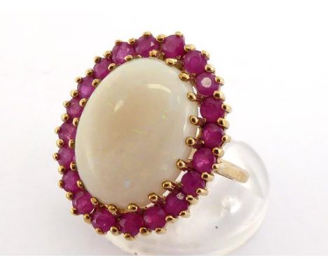 A 9 carat gold, opal and ruby cluster ring, the central oval cabochon 15 x 11mm, in a surround of round cut rubies, the shank