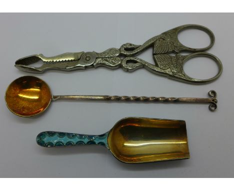 An enamelled Russian caddy spoon, one other spoon and a pair of sugar nips