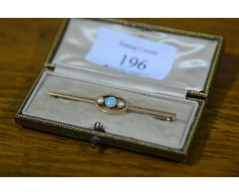 An early 20th century 15ct gold bar brooch set with an opal flanked by a pair of seed pearls, cased. 57mm