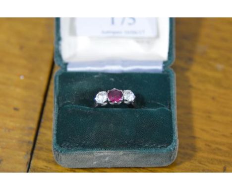 A three stone ruby and diamond ring, the central round-cut ruby claw-set between a pair of round brilliant-cut diamonds, on a
