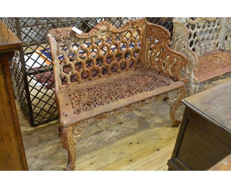 A cast iron two seater garden bench in the Coalbrookdale style, weathered, the back and seat cast with scrolls and flowerhead