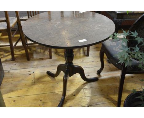 A George III oak tilt top tripod table, the circular top on a turned standard, with pointed pad feet. 69cm by 73cm