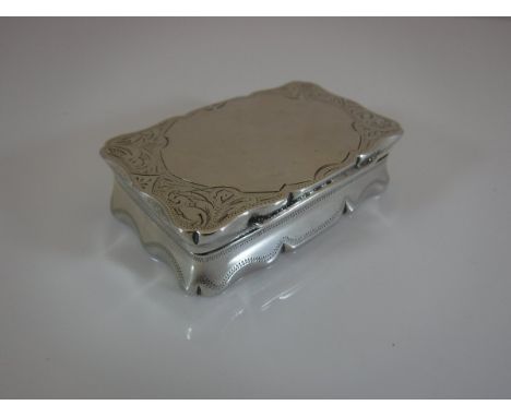 A Victorian silver snuff box of waisted rectangular form with all over engraved decoration opening to reveal a gilt washed in