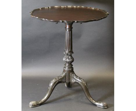 A circa 1900 mahogany snap top tea table, the circular top with pie crust rim, on a turned fluted and acanthus carved pedesta