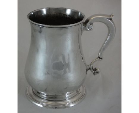 A George II silver baluster shaped mug with scroll work handle, raised on a circular foot (by Thomas Whipham and William Will