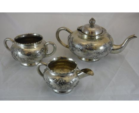 A three piece Chinese silver tea set, the teapot of squat round form decorated with birds on prunus blossom set branches, rai